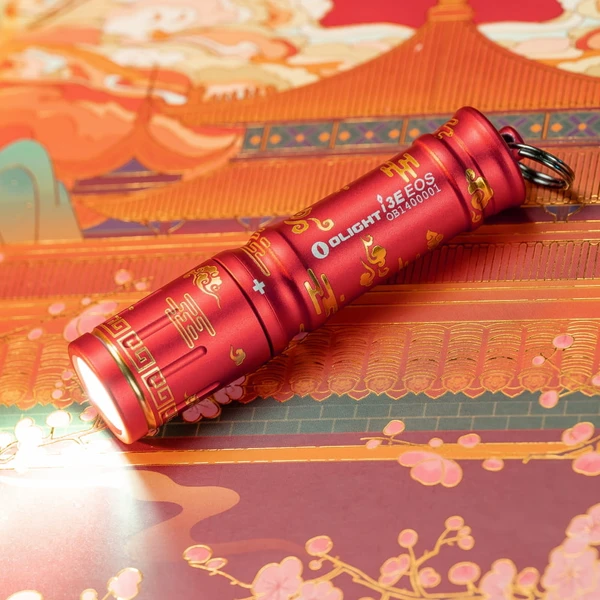 Red Olight 3E EOS flashlight with gold Chinese patterns, shining brightly on a vibrant oriental background.