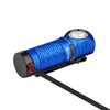 Blue Olight Perun 2 Mini tactical headlamp being charged, featuring a magnetic tailcap and textured body.