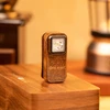 Olight compact bronze EDC flashlight standing on a wooden surface with a warm, cozy background.