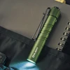 Olight Green i3T EOS Flashlight with Pocket Clip Glowing on Black Fabric for Everyday Carry EDC Use