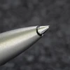 Detailed close-up of a brushed silver pen or stylus tip, showing its precision point against a dark background.