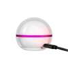 Spherical white night light with a pink accent stripe charging via USB cable on a white background