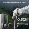 Portable high pressure camping shower head spraying water outdoors with mountain background