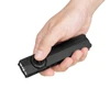 Hand holding Olight Arkfeld Pro flat EDC flashlight with thumb on the selector switch against a white background