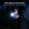 Person holding a blue thermal imager with built-in LED light shining brightly in a dark forest.