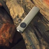 Olight Olive Green Arkfeld Ultra Flat Flashlight Lit on Rocky Terrain for Outdoor Adventure EDC Use