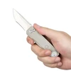 Hand holding a titanium pocket knife with an integrated LED flashlight tail light on a white background