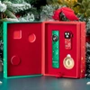 Festive Olight gift box displaying red and green flashlights with snowflake patterns and a gold coin.